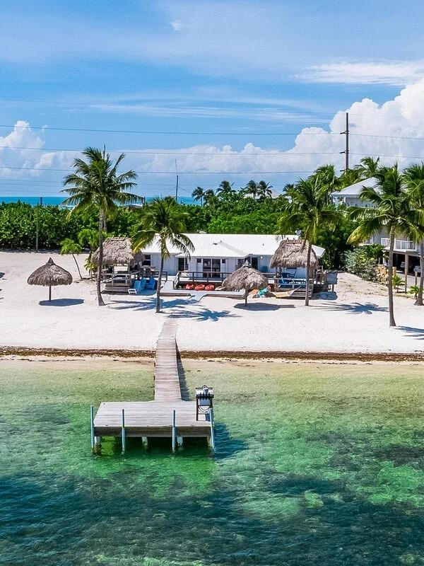 Florida Keys vacation rental with a private boat dock, canal water, palm trees, and waterfront outdoor space